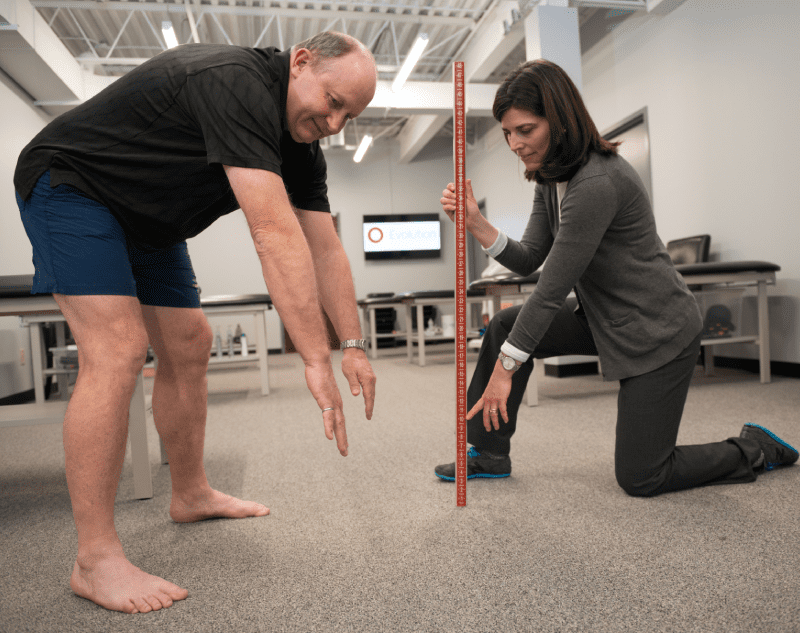 They are both focused on the task, with the man holding the ruler and the woman looking at the measurement