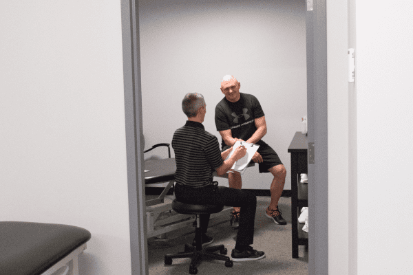 two men standing in a room, engaged in a conversation