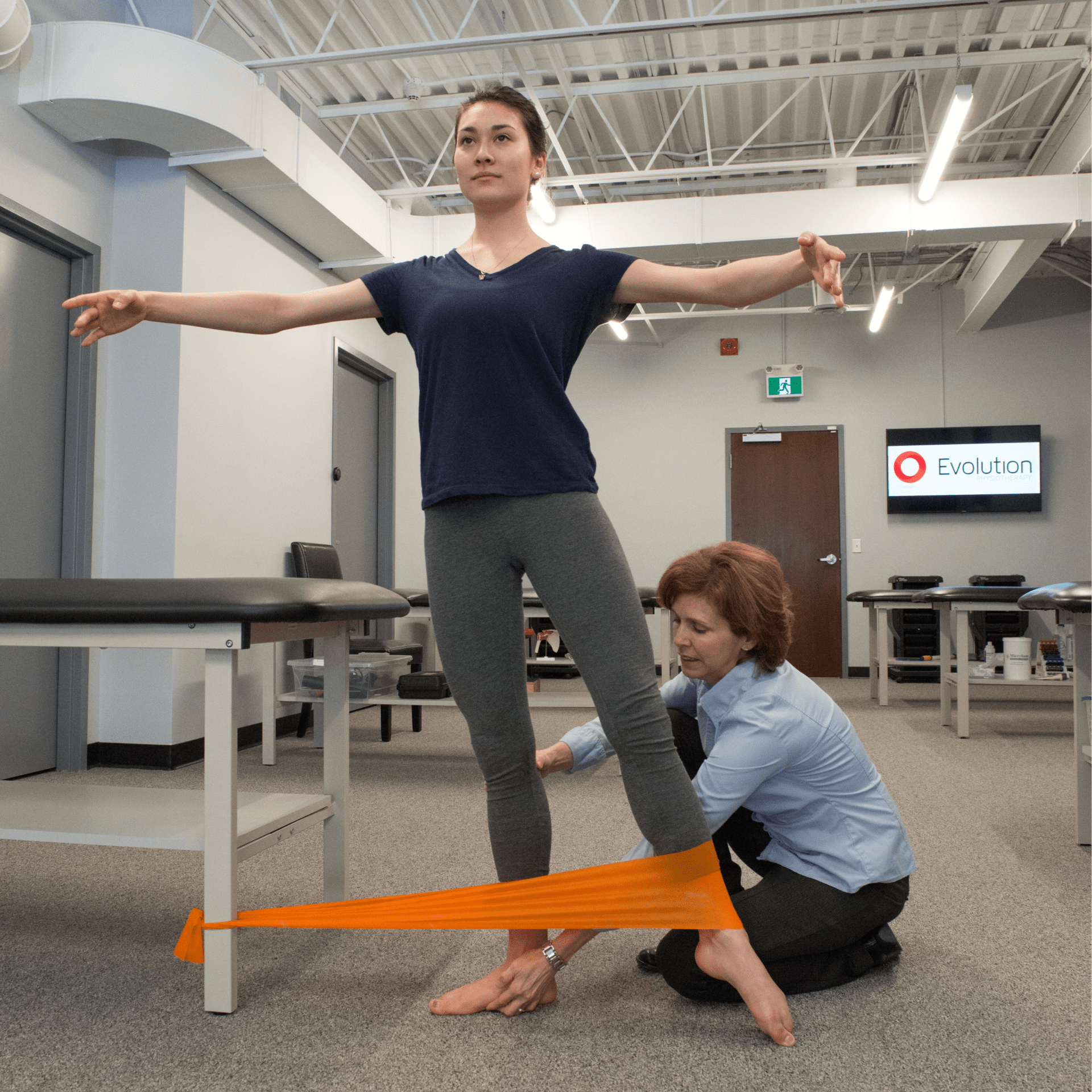 She is holding onto a long orange band or tape, which appears to be a resistance band or a piece of exercise equipment